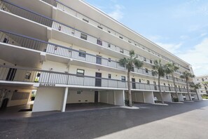 A multi-story hotel with balconies, an elevator, and a parking area.