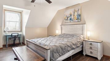 A bedroom with a bed, desk, chair, and nightstands.
