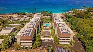A hotel with a rooftop pool and solar panels, overlooking a beach and ocean.