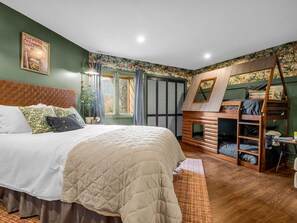 A bedroom with a large bed, a wooden loft bed, a window with curtains, and a poster on the wall. - Stylish waterfront 2 bedroom condo in Rumbling Bald at Lake Lure (Lake Lure)