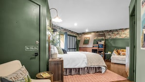 Une chambre avec un lit superposé, une table de chevet avec une lampe, une chaise avec un coussin et une petite table avec un livre.