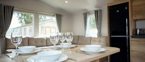 A dining area with a wooden table set for four, including wine glasses, plates, and cutlery.