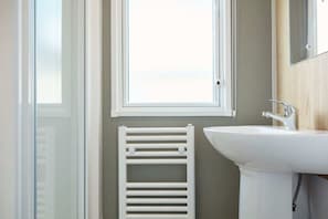 A bathroom with a white radiator, a sink, and a window.