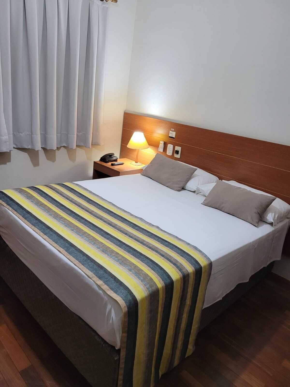 A hotel room with a large bed, a nightstand with a lamp, and a wooden headboard.