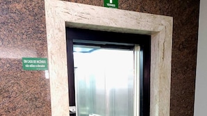 An elevator with a granite wall and a sign indicating not to use the elevator in case of fire.