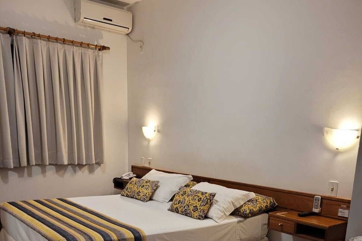 Une chambre d’hôtel équipée d’un lit, de tables de chevet, d’un réfrigérateur et d’un appareil de climatisation.