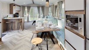 A modern kitchen with a dining area, wooden bar stools, and a built-in oven.