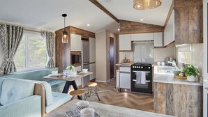 A modern kitchen with wooden cabinets, a built-in oven, and a dining area with a light blue sofa and a table set for two.
