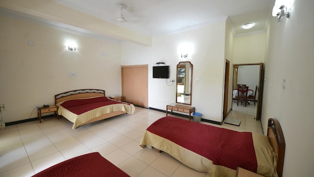 Habitación de hotel con dos camas, un televisor, un espejo y una mesita.