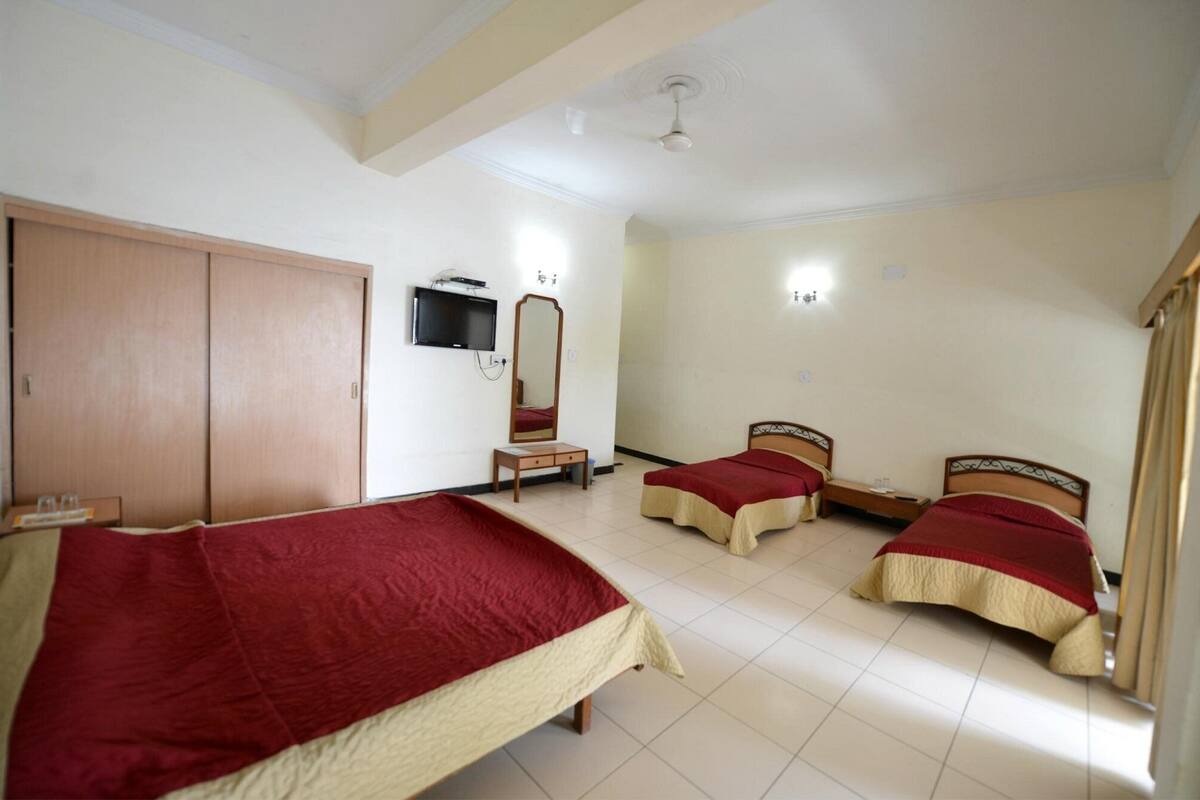 Une chambre d’hôtel avec deux lits simples, une télévision, un miroir et une armoire.