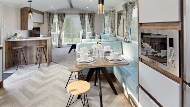 Een moderne keuken met een eethoek, houten barstoelen en een ingebouwde oven.