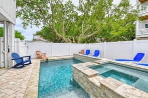 A backyard with a swimming pool, stone steps, and a white fence.
