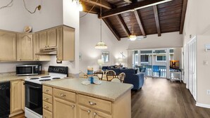 A spacious kitchen with wooden cabinets, a central island, and a dining area with a blue sofa and wooden chairs. - ☀️Walk to Beach-Pet Friendly-Great Amenities-Pool-Chateau La Mer #7D☀️ (Destin)