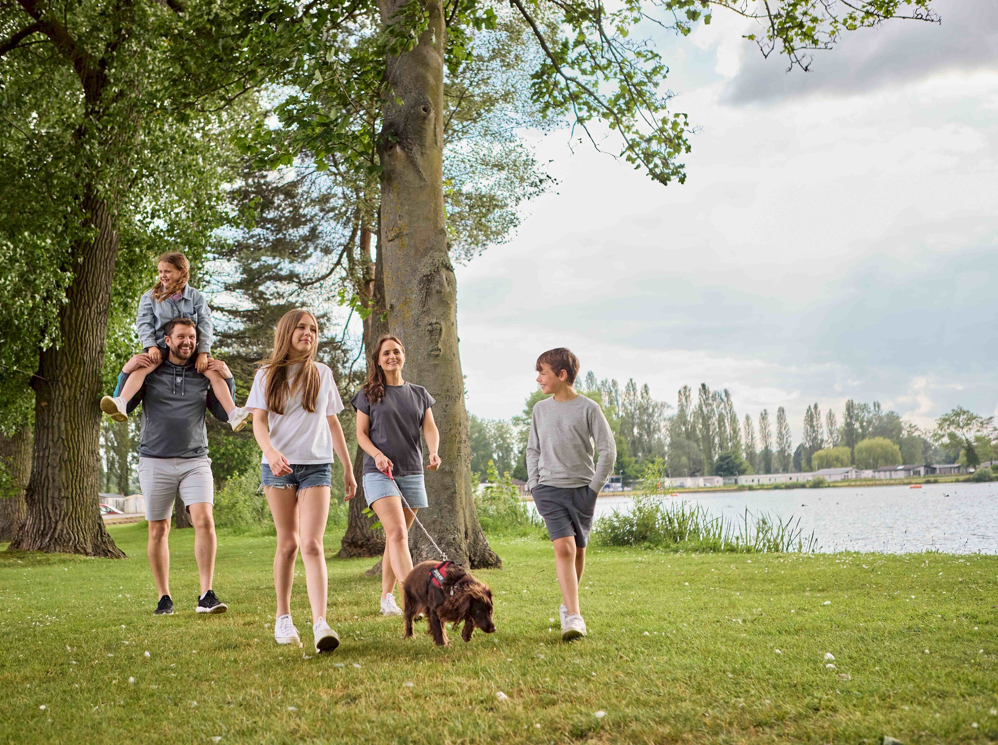 Una familia caminando en un parque con un lago al fondo.