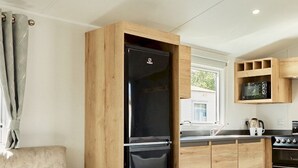 A compact kitchen with wooden cabinetry, a black refrigerator, a microwave, and a stove.