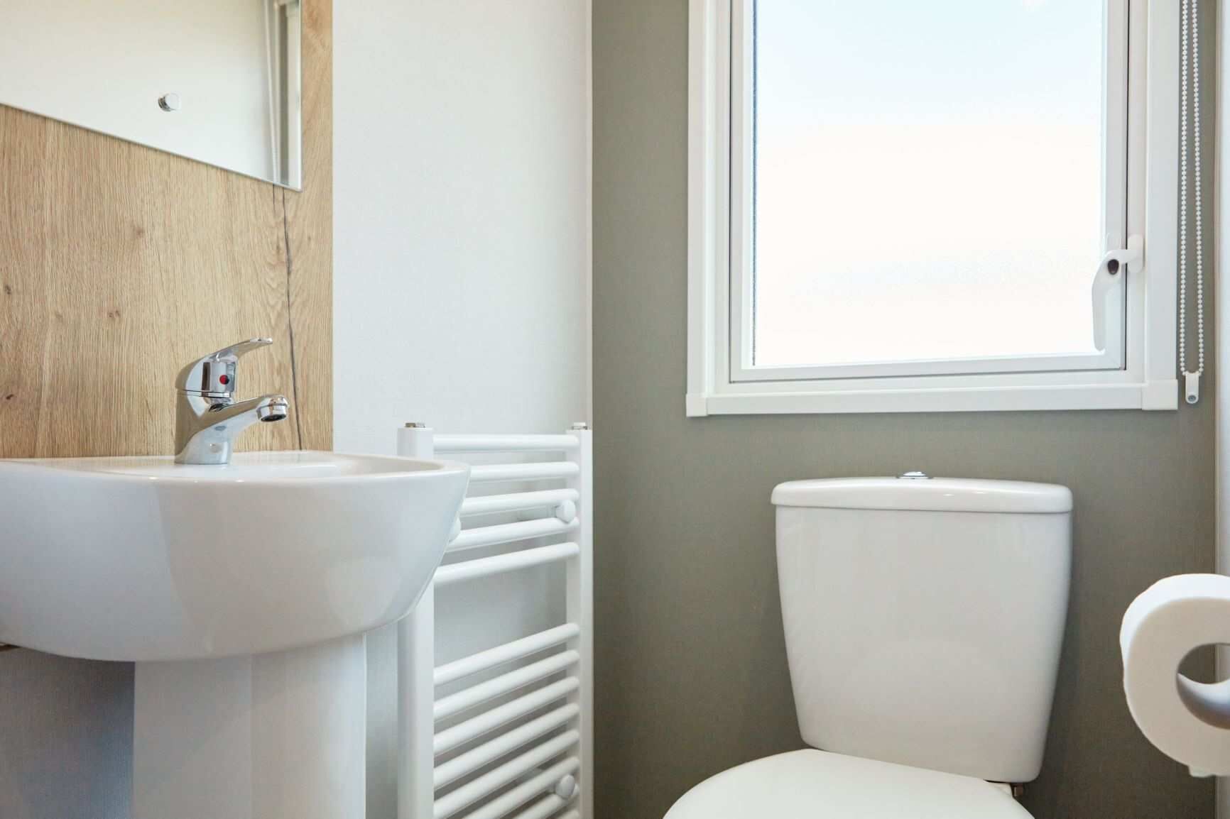 Un baño con lavamanos blanco, inodoro y ventana.