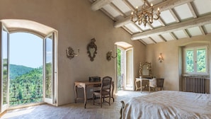 A bedroom with a large bed, a desk, and a chair, with a view of the outdoors. - Col Di Casale - A breathtaking Umbrian villa in the green heart of Italy. (Pietralunga)