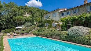 A swimming pool with lounge chairs and a stone building surrounded by lush greenery. - Col Di Casale - A breathtaking Umbrian villa in the green heart of Italy. (Pietralunga)