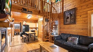 A log cabin interior with a living room, kitchen, and a staircase. - Mama Bear Paw w/ private hot tub, two pools (Pigeon Forge)
