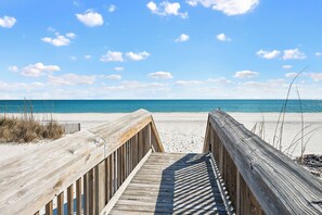 A wooden boardwalk leading to a beach with a clear blue sky.