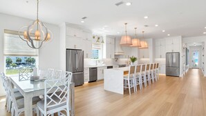 Una cocina moderna con armarios blancos, electrodomésticos de acero inoxidable y una isla central con asientos.