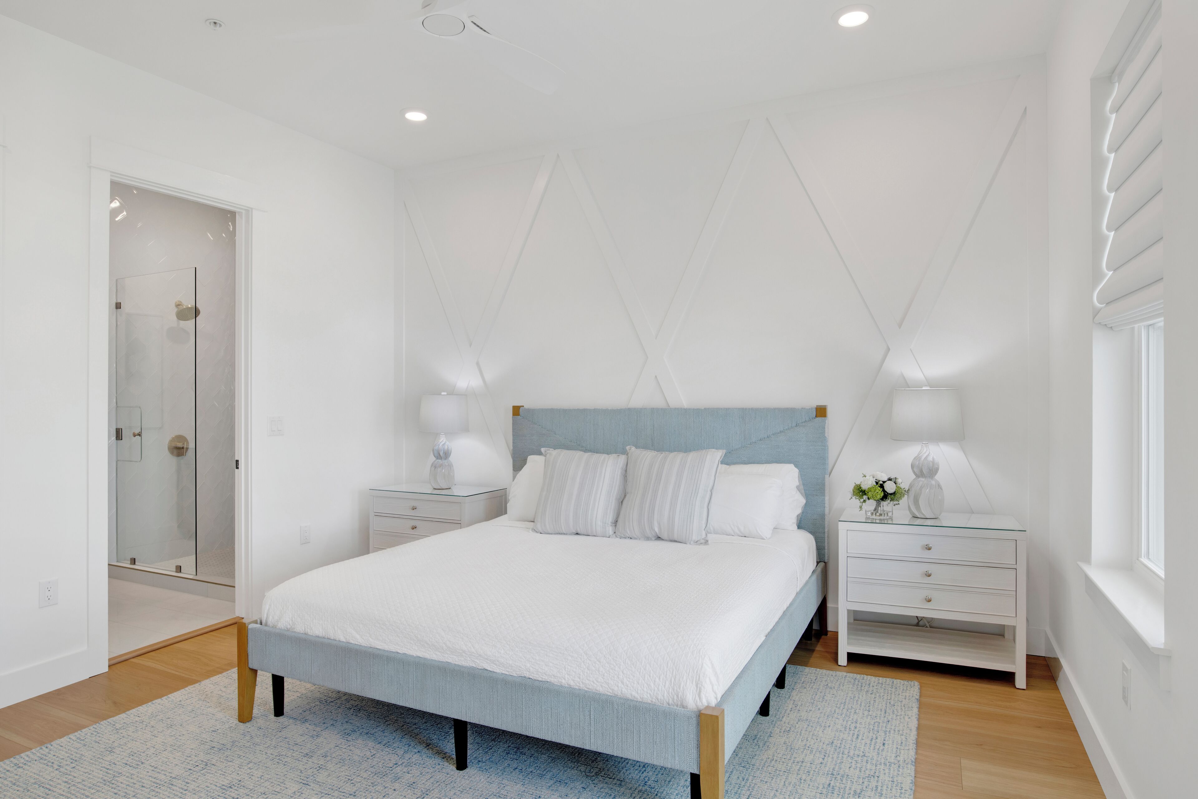 A modern bedroom with a large bed, bedside tables, and a window.