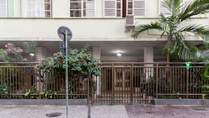 A gated entrance with a metal fence, a satellite dish, and a potted plant with red flowers. - Comfort in Ipanema 6 Minutes From the Beach J302 (Rio de Janeiro)