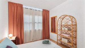 A bedroom with a bed, a nightstand, a lamp, a wardrobe, and a wicker shelf. - 2 Bed Island Retreat-sleeps 4-5 Min Walk To Beach (Santa Cruz de la Palma)