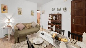 A dining area with a table set for two, a sofa, and a bookshelf. - 2 Bed Island Retreat-sleeps 4-5 Min Walk To Beach (Santa Cruz de la Palma)