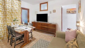 A living room with a television, a dining table with chairs, a sofa, and a patterned curtain. - 2 Bed Island Retreat-sleeps 4-5 Min Walk To Beach (Santa Cruz de la Palma)