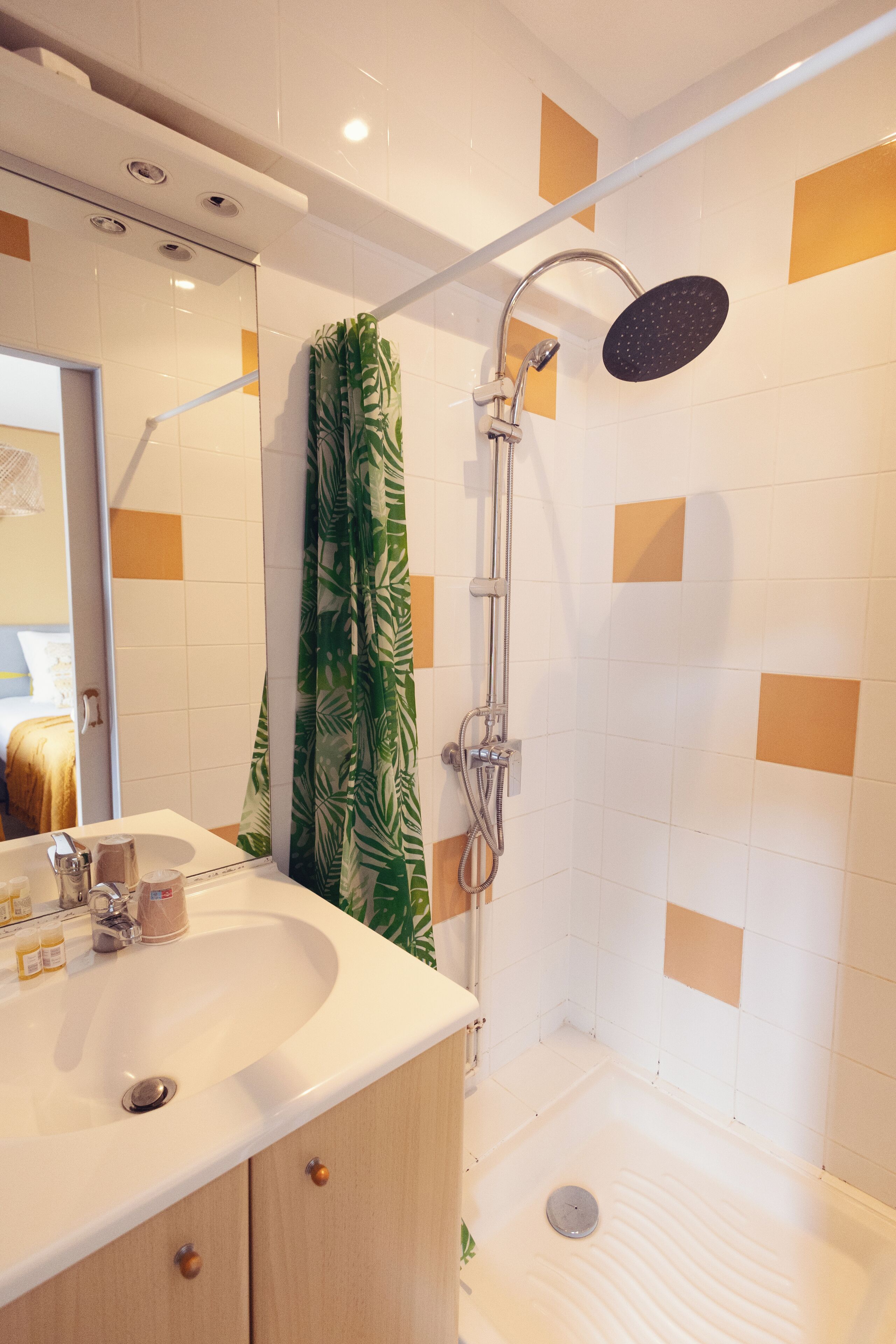 Un baño moderno con ducha, lavamanos y espejo.