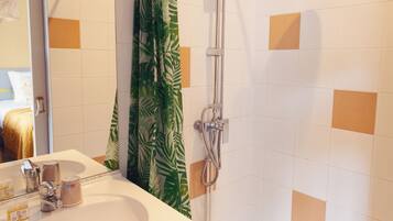 Un baño moderno con ducha, lavamanos y espejo.