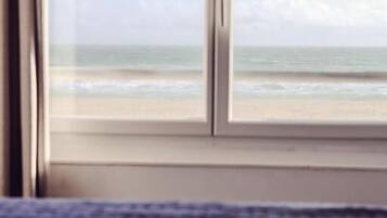 Une pièce dotée d’une grande fenêtre donnant sur une plage.