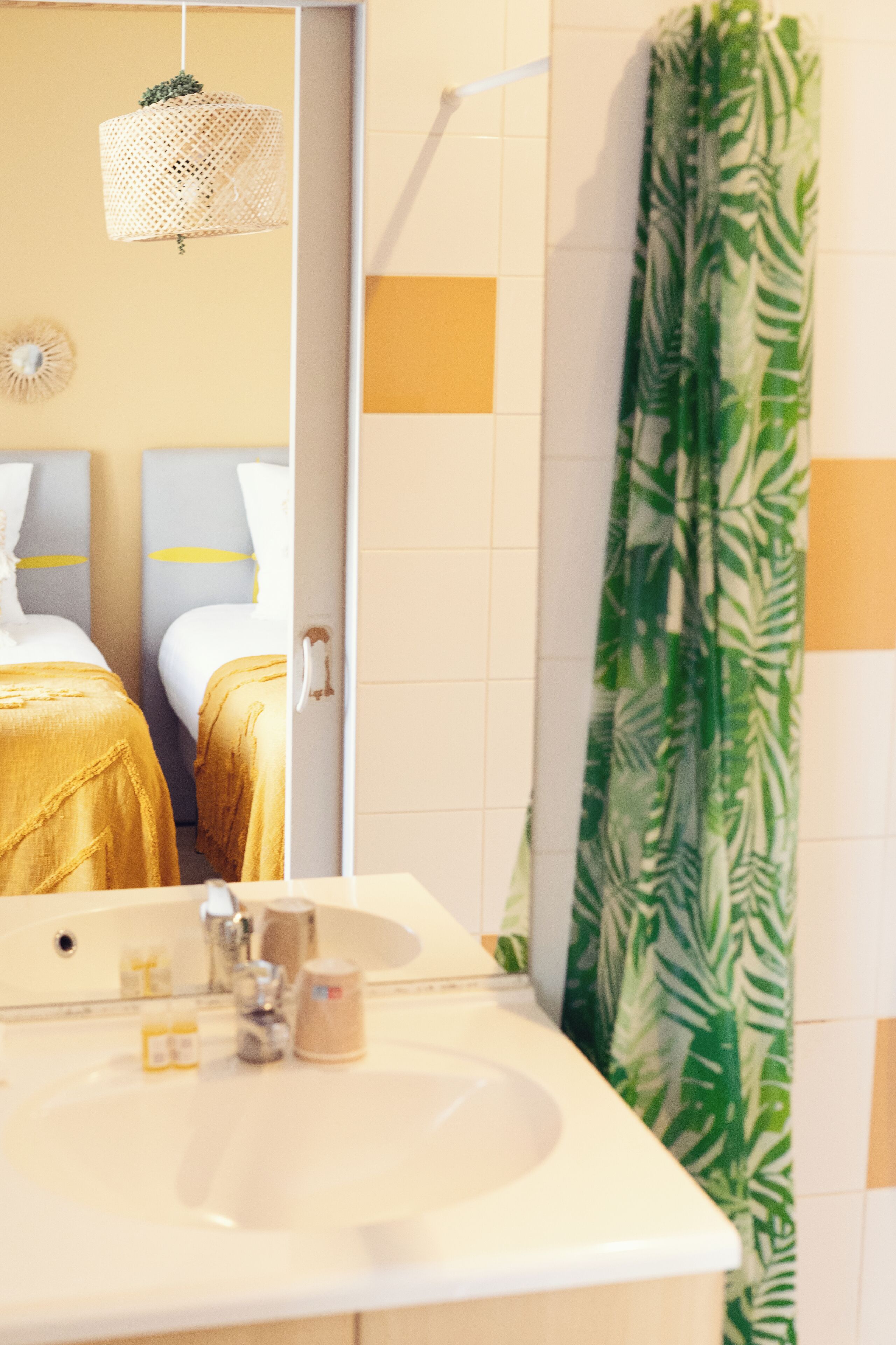 Ein Badezimmer mit Waschbecken, Spiegel und einem Duschvorhang mit grünem Muster.