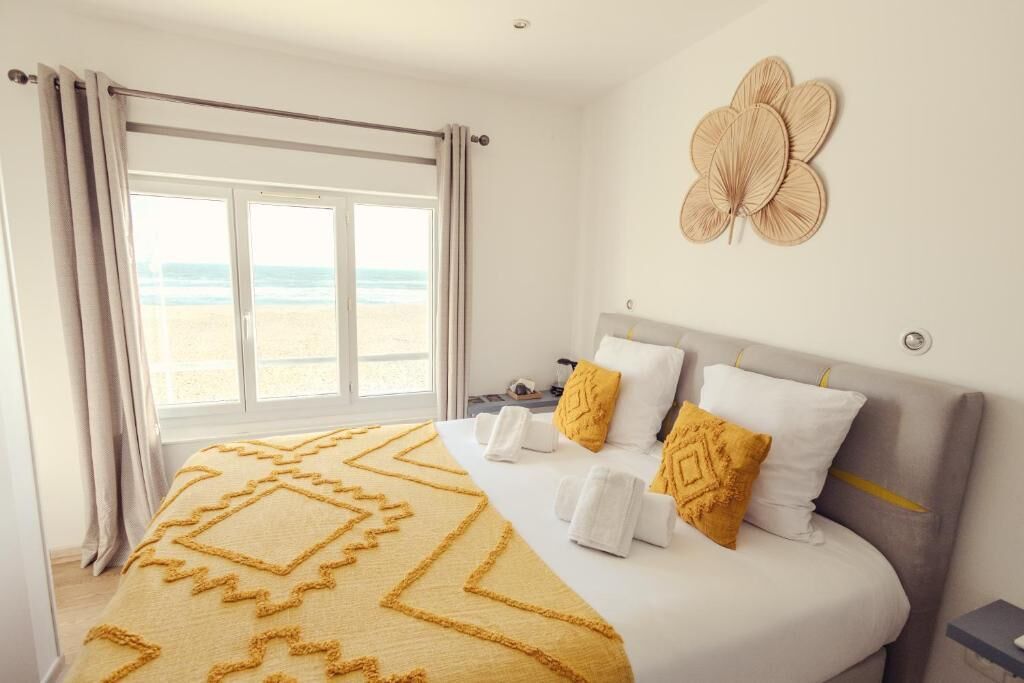 Un dormitorio con una cama, una ventana con cortinas, un adorno en la pared y una mesita de noche.
