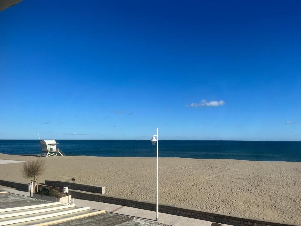 A beach with a lifeguard tower and a clear blue sky.