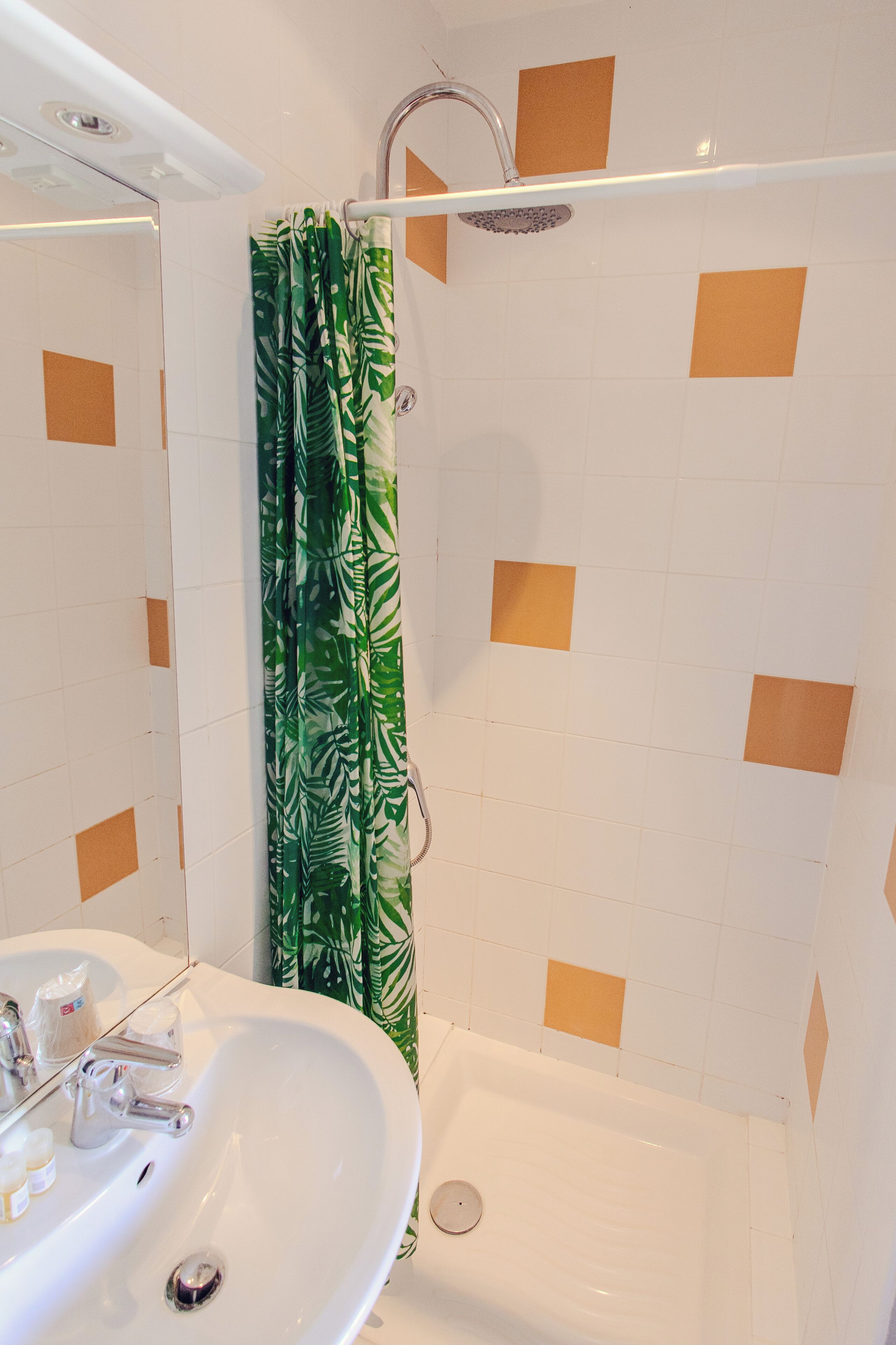 A bathroom with a white sink, mirror, and shower area.