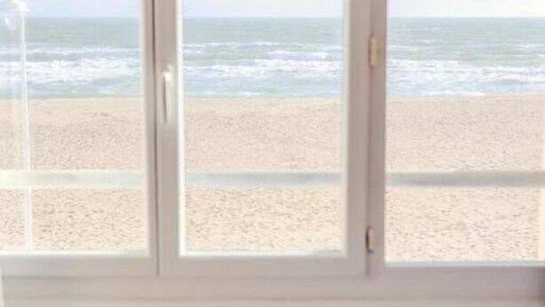 A room with a large window overlooking a beach. - La Côte Révéé (Leucate)