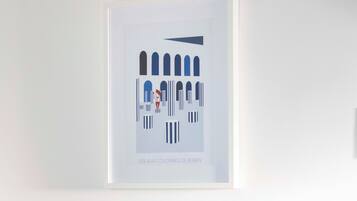 A framed artwork depicting a building with arches and columns, and a brown handbag on a blue bench below.