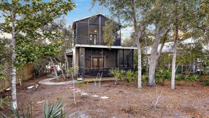 A modern house with a large glass facade, surrounded by trees and a landscaped garden.