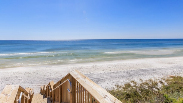 A wooden beach deck with a staircase leading to a beach.