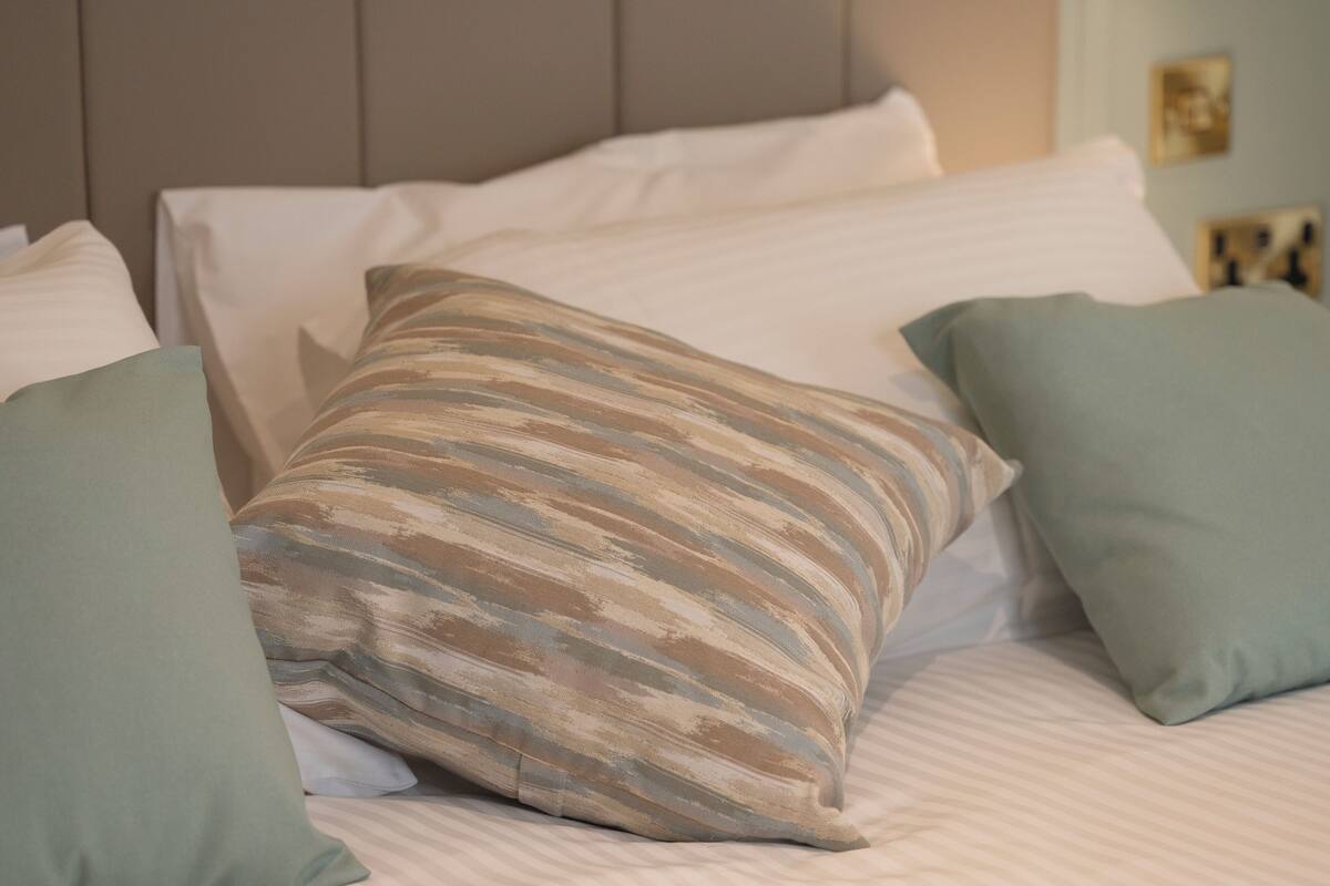 Una cama con almohadas a rayas y un cabecero sencillo.