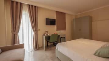A hotel room with a bed, a desk with a chair, a television, and a wardrobe.