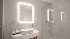 Un baño moderno con lavamanos de mármol blanco, ducha con mampara de vidrio y espejos iluminados.