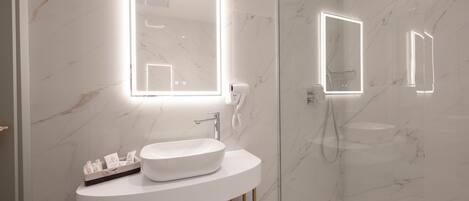 A modern bathroom with a white marble sink, a glass-enclosed shower, and illuminated mirrors.