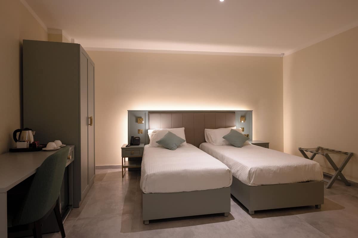 Una habitación de hotel con dos camas, un escritorio y un armario.