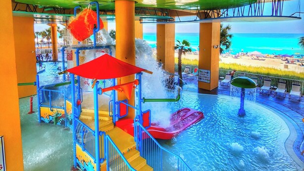 Parque acuático con piscina, toboganes y zona de playa.