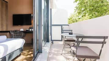 Une chambre moderne équipée d’un lit, d’une télévision, d’une petite table et d’une chaise.