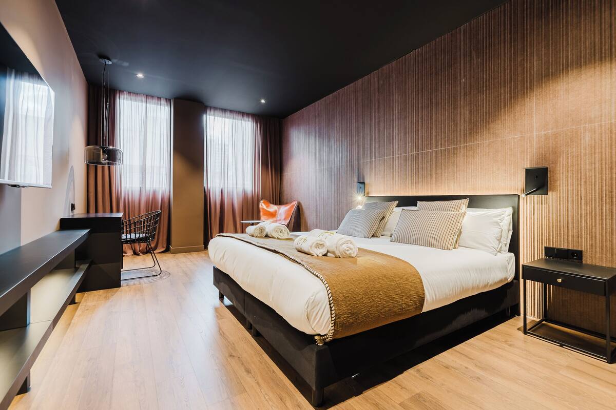 A modern hotel room with a large bed, a desk, and a chair.