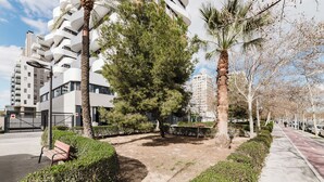 A modern urban setting with a curved building, a palm tree, and a paved walkway. - Hotel Arena Select (València)